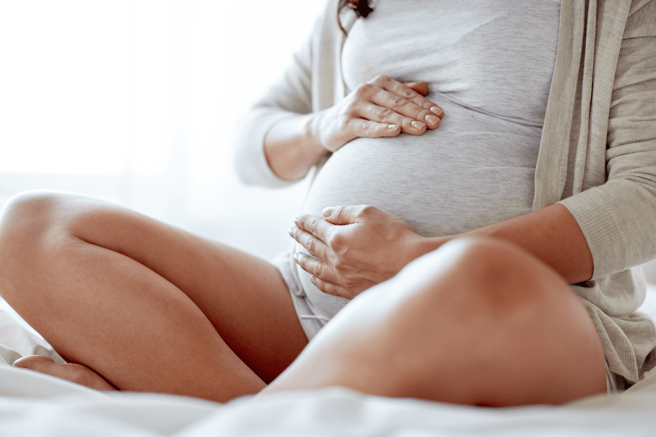 Pregnant woman sitting criss cross and holding her stomach