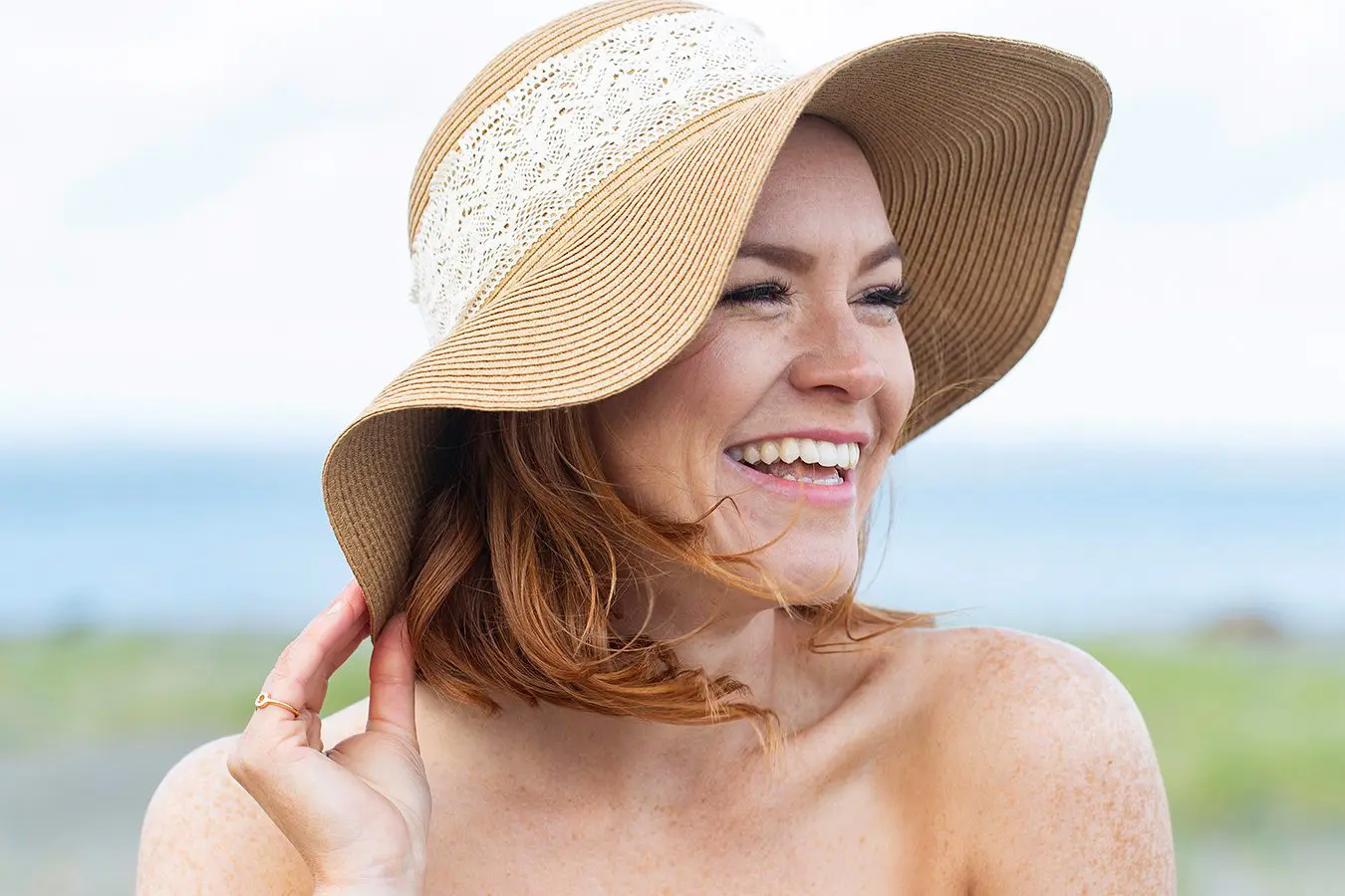pretty woman with red hair and freckles wearing a sun hat