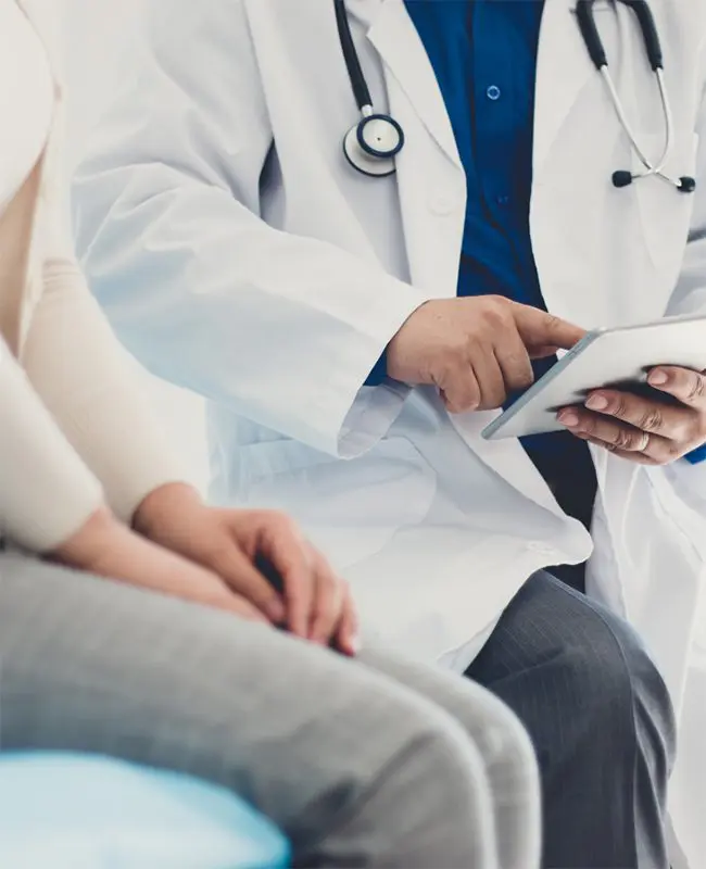 urgent care physician reading results of test on device with female patient