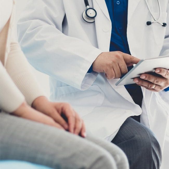 urgent care physician reading results of test on device with female patient